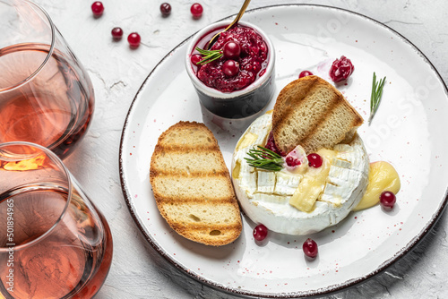 French cuisine. Baked camembert cheese with cranberries and basil leaves, wine on a light background, banner, menu, recipe place for text