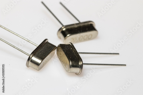 Crystal resonator in metal body on white background. Electronic components.