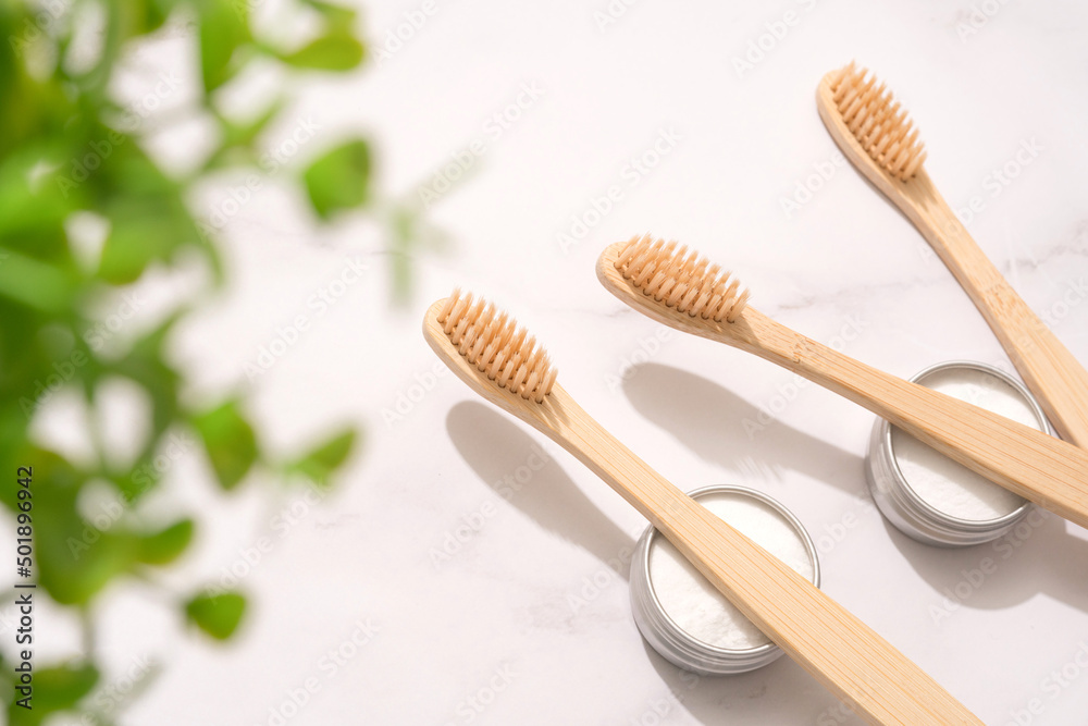 Natural wooden bamboo toothbrushes and mineral toothpowder, kaolin in metal containers on white table background. Natural bath products, organic dentifrice. Mockup image. Top view Natural wooden bamboo toothbrushes and mineral toothpowder, kaolin in metal containers on white table background. Natural bath products, organic dentifrice. Mockup image. Top view