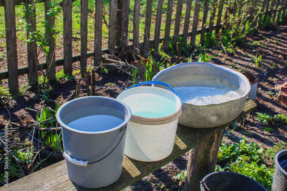 Various iron and plastic utensils with clean water on a wooden bench Various iron and plastic utensils with clean water on a wooden bench