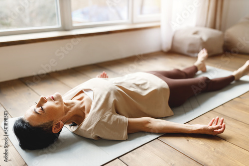 Mature woman meditating in Corpse pose photo