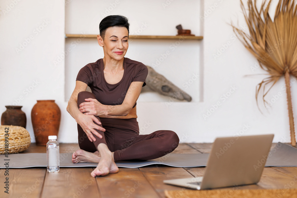 Obraz premium Middle aged sportswoman watching tutorial video