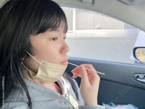 綿棒を使って車内でPCR検査する女性