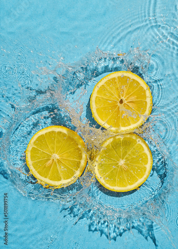 Trend contemporary concept organic juicy fresh lemon in fresh liquid water with splashes. Top view and idea of summer and health.