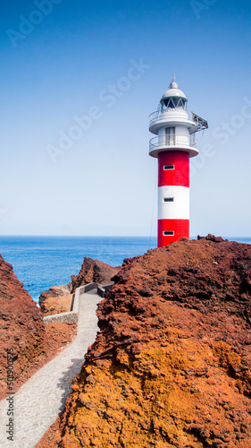 Obraz na płótnie Beautiful red and white lighthouse building on volcanic shore of Tenerife Island in Spain. Atlantic Ocean background, vertical photo. w salonie