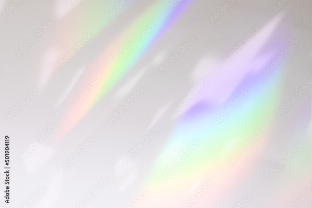 Blurred rainbow light refraction texture overlay effect for photo and mockups. Organic drop diagonal holographic flare on a white wall. Shadows for natural light effects