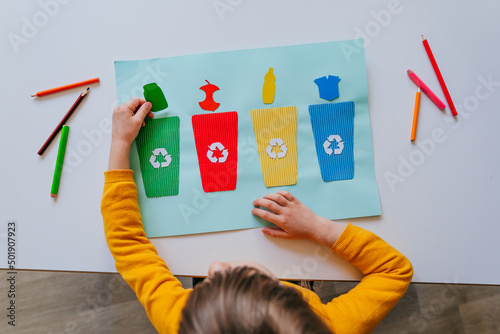 Photography Little girl playing with poster of garbage containers for sorting at kindergarte