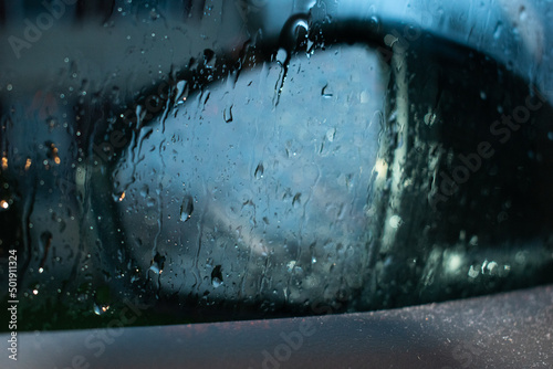 Wet Rearview mirror and window on a rainy evening (ID: 501911324)
