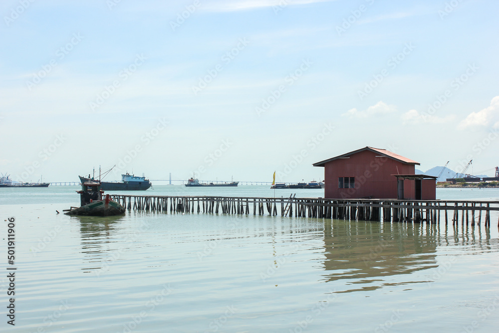 Fototapeta premium Pier with a wooden stilt house in the ancient seaside clan jetty in the UNESCO heritage town of Georgetown in Penang.