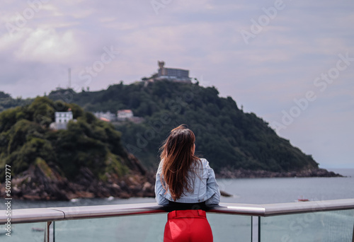 Young brunette girl from behind looking at the sea in summer