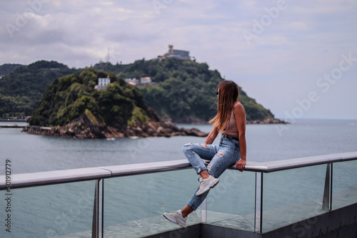 Young brunette girl from behind looking at the sea in summer