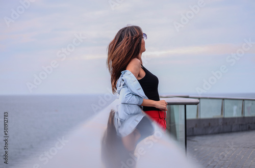 Young brunette girl from behind looking at the sea in summer