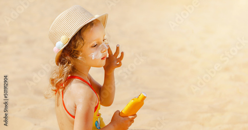 Принти на полотні The child holds a bottle of moisturizing Sunscreen in his hands and puts a protective layer on his face