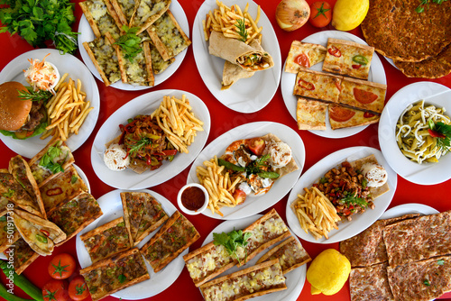 Table scene of assorted take out or delivery foods. Pizza, hamburgers, Doner, fried chicken and sides. Top down view on a table.