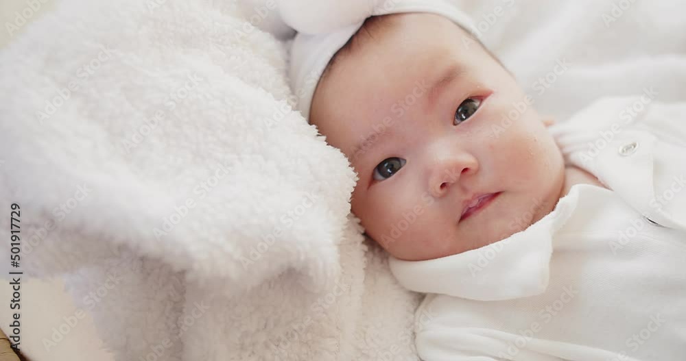 cute adorable Asian baby infant girl lying on comfortable bed and looking at camera cute adorable Asian baby infant girl lying on comfortable bed and looking at camera