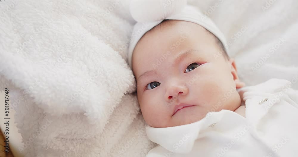 cute adorable Asian baby infant girl lying on comfortable bed and looking at camera cute adorable Asian baby infant girl lying on comfortable bed and looking at camera
