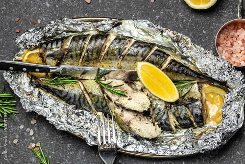 Fried or baked mackerel fish with lemon herbs and spices on a dark background, banner, Food recipe background. Close up, top view