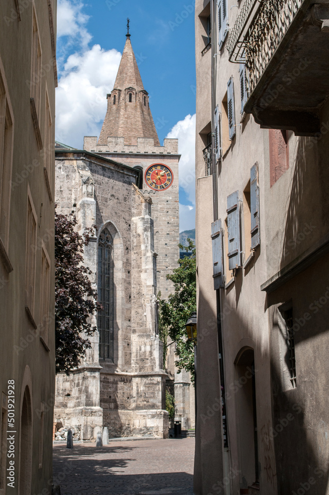 Old stone church with tower and clock in the city of Sion in Switzerland.
