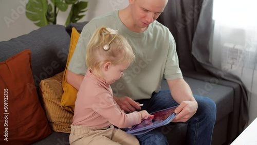 A child with cochlear implants plays with a tablet computer with his father. Deafness and medical technology concept photo