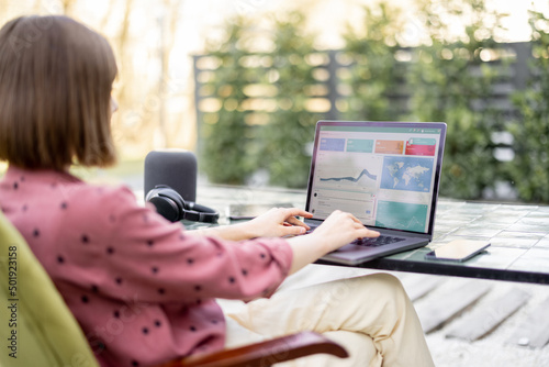 Εκτύπωση καμβά Young woman works on laptop while sitting by the table outdoors