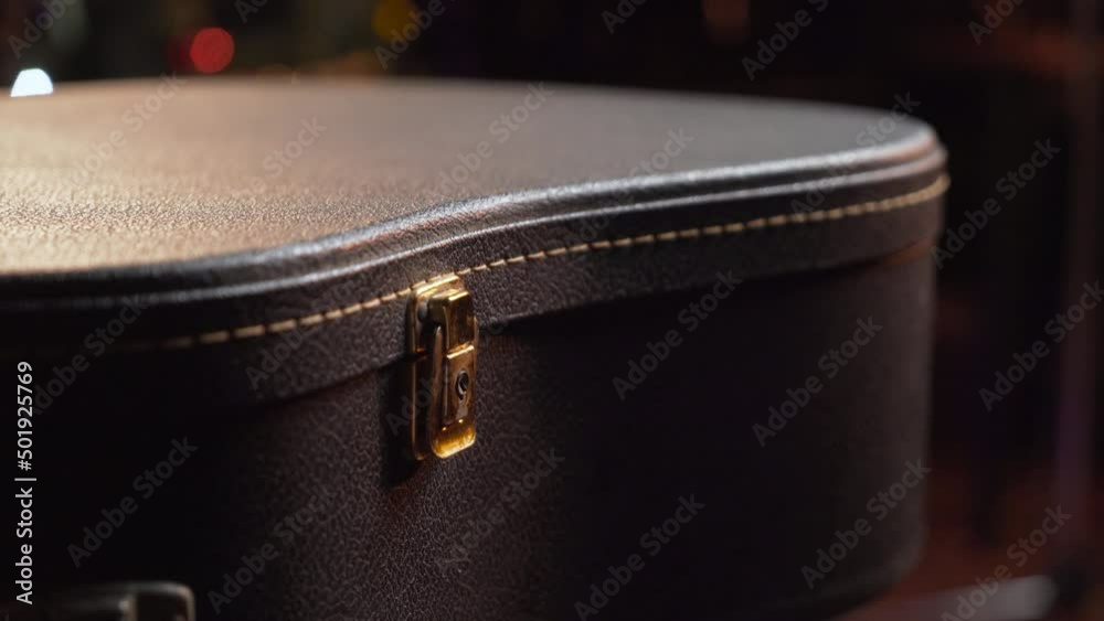 The guitarist closes the latch of the corrugation for the guitar in close-up. A case for a musical instrument. Opening guitar case