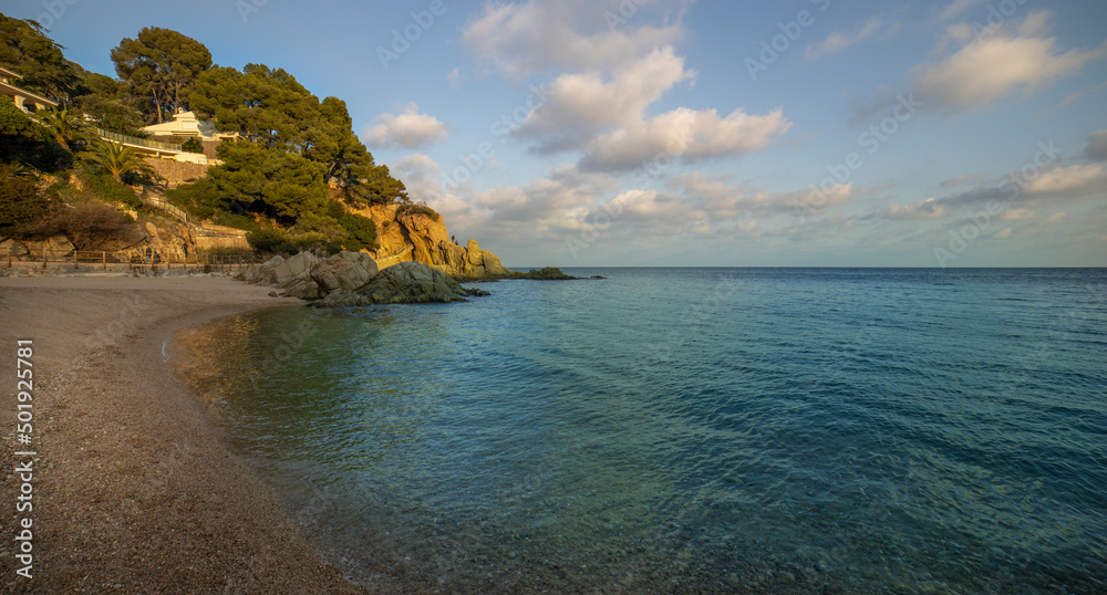 Fototapeta premium Evening seascape with coastline illuminated by sunlight. View of the sea and part of the land.