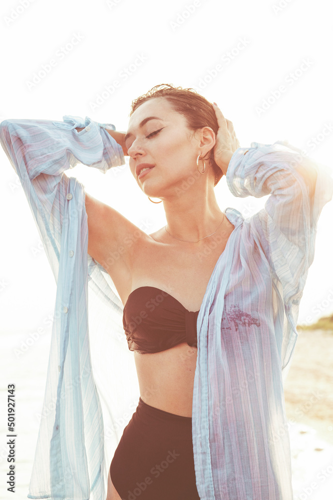 Portrait of a beautiful girl in a swimsuit and a white shirt posing in the sea. Summer vacation concept. Portrait of a beautiful girl in a swimsuit and a white shirt posing in the sea. Summer vacation concept.