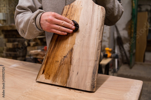 Closeup of Carpenter coating a wooden cutting board with protective flaxseed oil