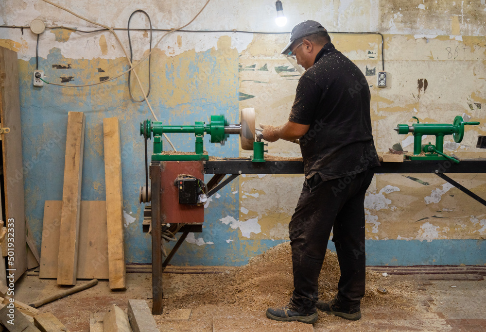Carpenter turning wood on a lathe in workshop Carpenter turning wood on a lathe in workshop