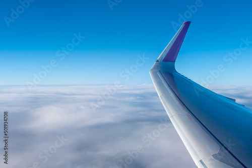 Wing of an airplane above the clouds. The view from the airplane window to the clouds and sunset.Airplane wing above thick white clouds. Wonderful breathtaking view.
