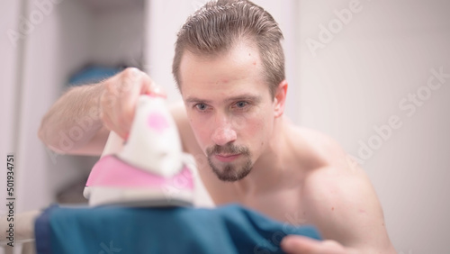 Shirtless sexy man careful ironing shirt with iron photo