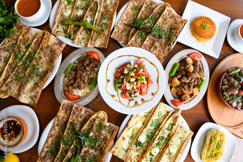 Traditional Turkish cuisine. Pizza, pita, pidesi, sucuk, hummus, kebab. Many dishes on the table. Serving dishes in restaurant. Background image. Top view, flat lay