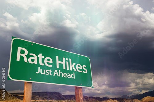 Fototapeta Rate Hikes Green Road Sign Over Dramatic Clouds and Sky.