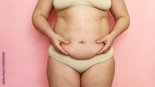 Wallpaper Mural Unrecognizable fat and overweight woman holding folds of skin on thick large belly, obesity female body on pink isolated background, studio shot. Waving stomach. Get rid of visceral fat, weight gain Torontodigital.ca