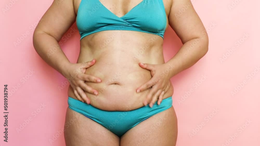 Cropped of overweight fat woman holding tummy flabs, excess fat in blue underwear. Fast gain weight, cellulite. Big stomach. Emphasizing excess adiposity. Pinching, palpating her belly, unhealthy diet Cropped of overweight fat woman holding tummy flabs, excess fat in blue underwear. Fast gain weight, cellulite. Big stomach. Emphasizing excess adiposity. Pinching, palpating her belly, unhealthy diet