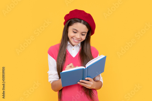 happy teen school girl in french beret making notes in planner notepad or notebook, writing