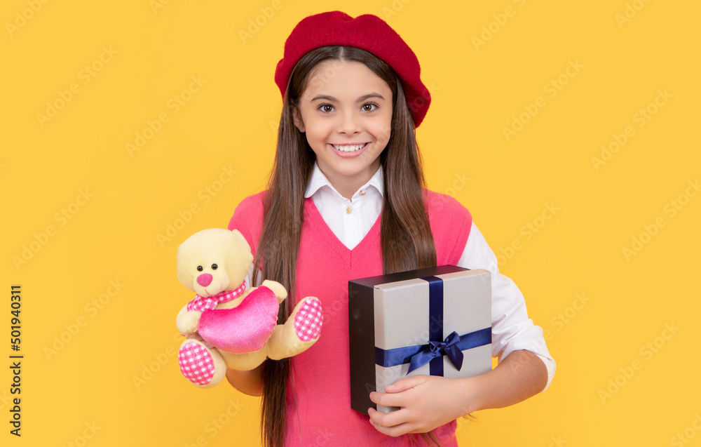 happy teen girl in french beret hold toy present and gift box on yellow background, black friday happy teen girl in french beret hold toy present and gift box on yellow background, black friday