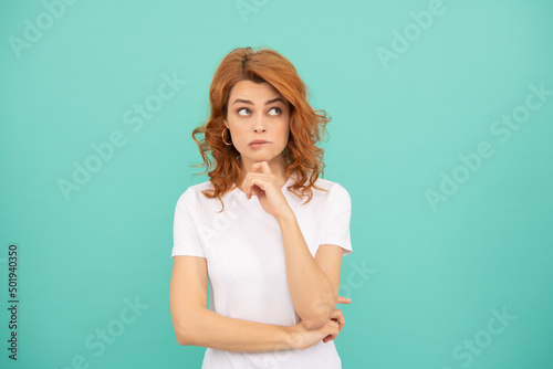 thinking redhead woman with curly hair on blue background
