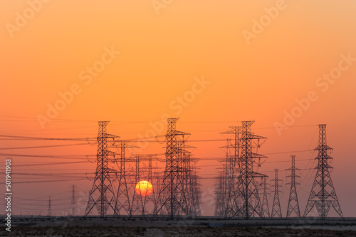 High-voltage power lines in Saudi Arabia (KSA) at sunset or sunrise. High voltage electric transmission tower. 
