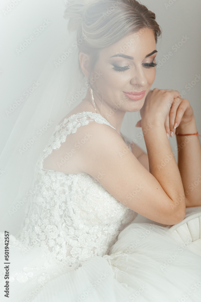 Beautiful bride sitting on the couch. Wedding hairstyle and makeup. Look down. Beautiful bride sitting on the couch. Wedding hairstyle and makeup. Look down.