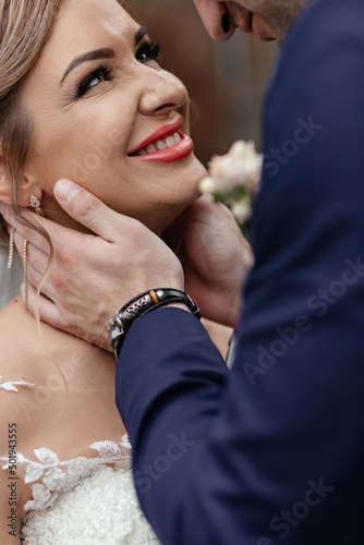 Groom touches bride's neck tender before a kiss