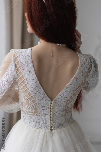 Beautiful young redhead bride in a white lace wedding dress wearing pearls on a special day, Close up portrait