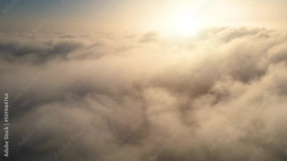 Aerial shot of flying over a layer of soft clouds at dawn