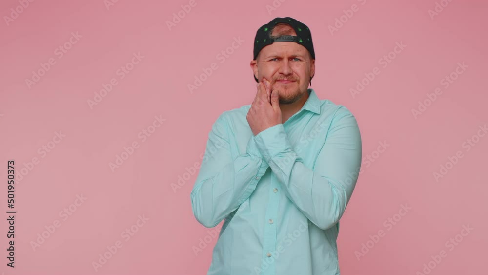 Bearded young man touching sore cheek suffering from toothache cavities or gingivitis waiting for dentist appointment, gums disease. Adult guy indoors studio shot isolated alone on pink background Bearded young man touching sore cheek suffering from toothache cavities or gingivitis waiting for dentist appointment, gums disease. Adult guy indoors studio shot isolated alone on pink background
