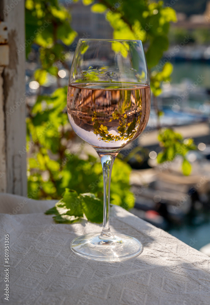 Rose wine in glass served on outdoor terrace with view on old fisherman's harbour with colourful boats in Cassis, Provence, France Rose wine in glass served on outdoor terrace with view on old fisherman's harbour with colourful boats in Cassis, Provence, France