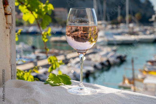 Rose wine in glass served on outdoor terrace with view on old fisherman's harbour with colourful boats in Cassis, Provence, France photo