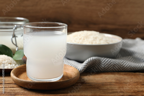 Glass of rice water on wooden table. Space for text