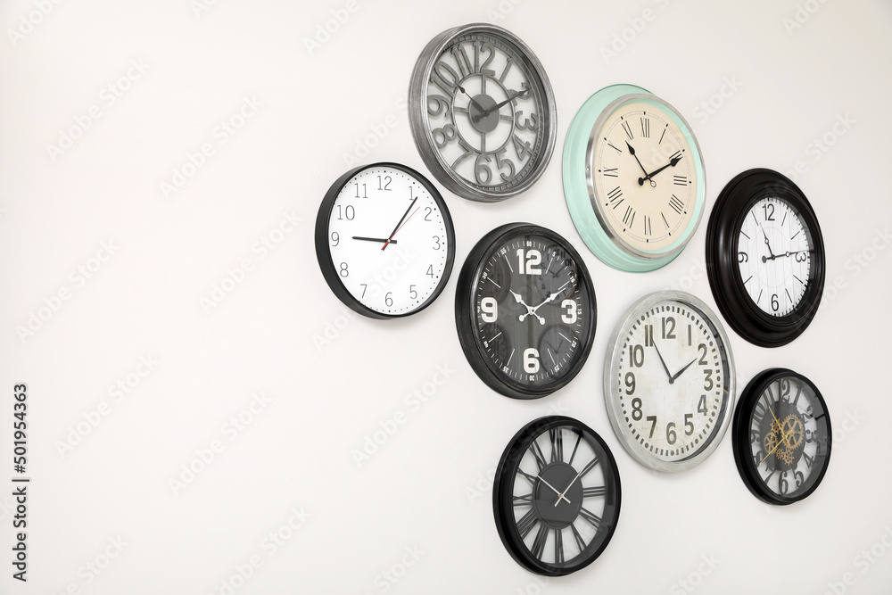 Many different clocks hanging on white wall. Many different clocks hanging on white wall.