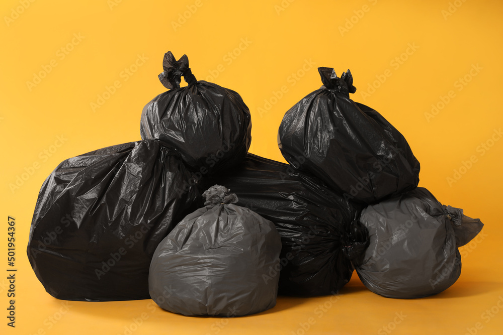 Trash bags full of garbage on yellow background