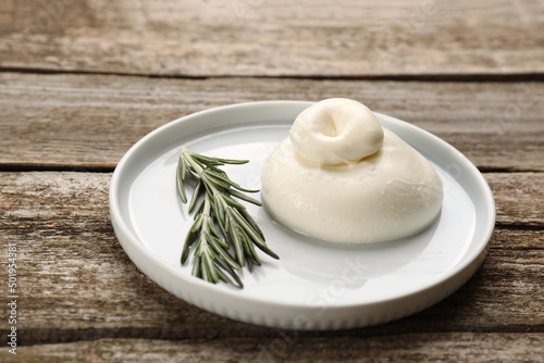 Delicious burrata cheese with rosemary on wooden table
